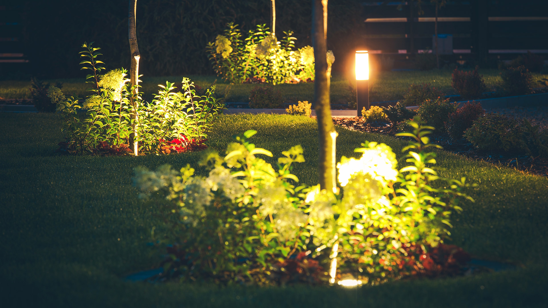 A few landscape beds lit up in the evening by a home in Saylorville, IA.