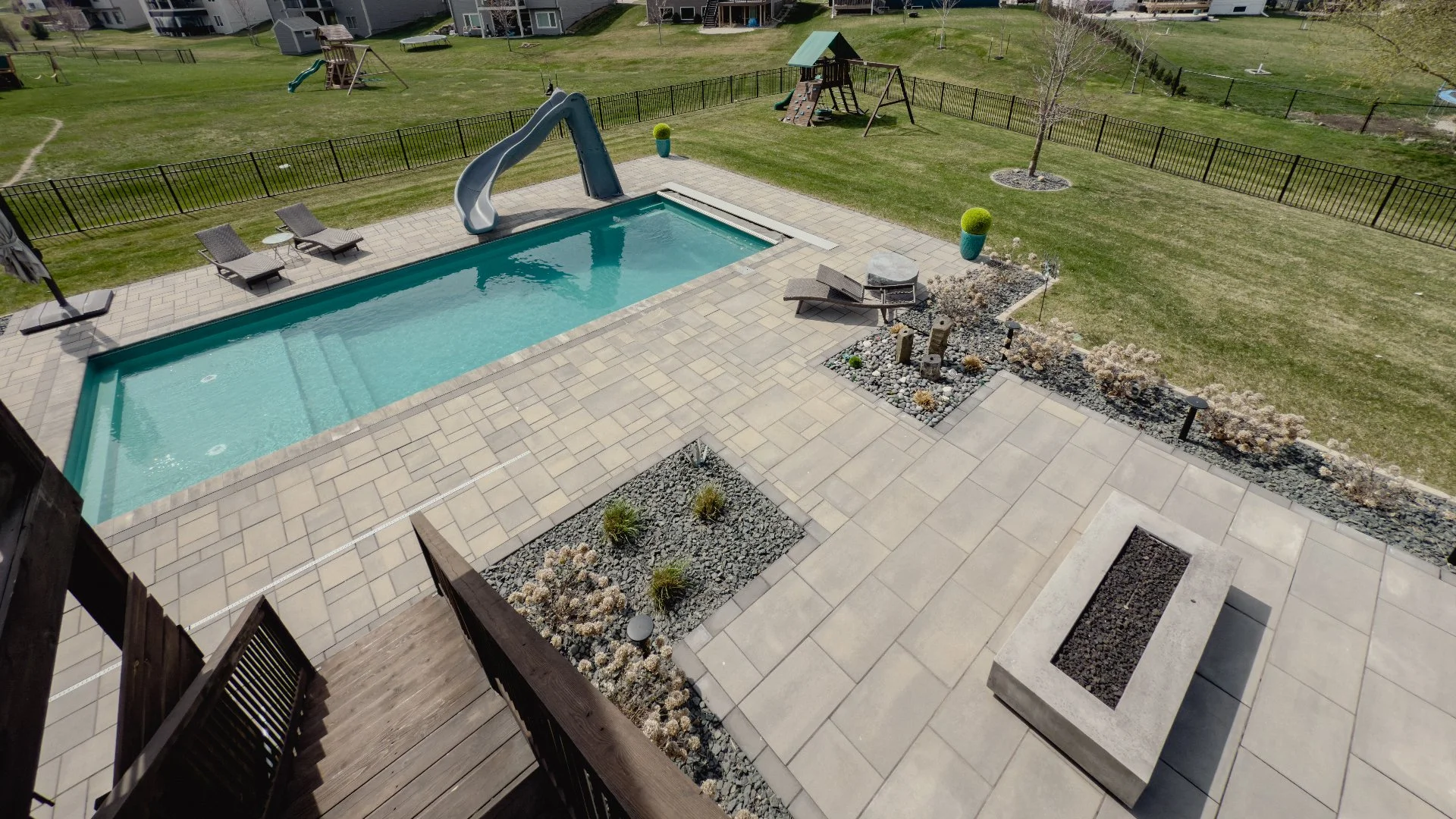 Paved patio with a firepit and a pool in backyard in Ankeny,IA.