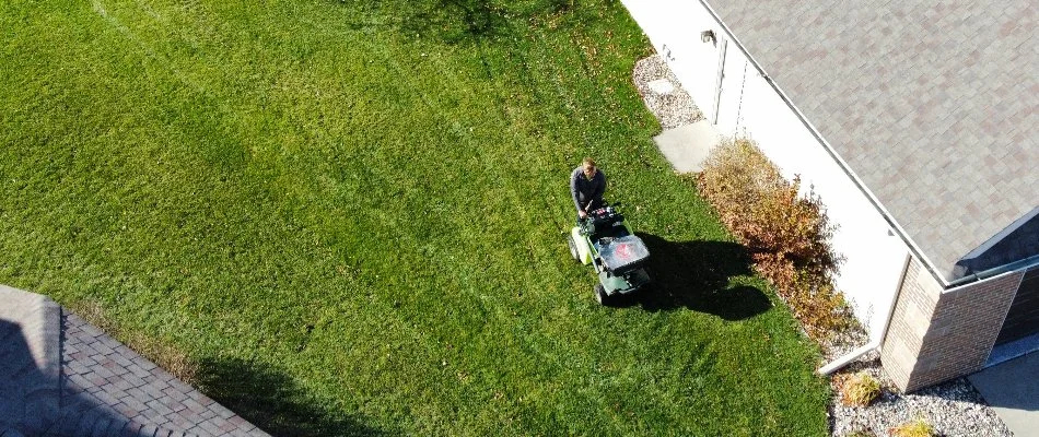 Man spreading granular fertilizer on a lawn in Ankeny, IA.