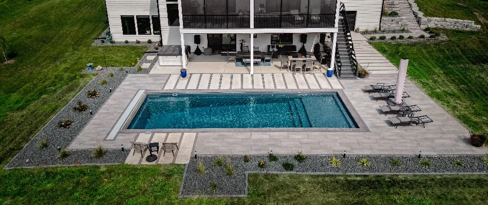 Pool in Ankeny, IA, with paver decking and landscape beds.