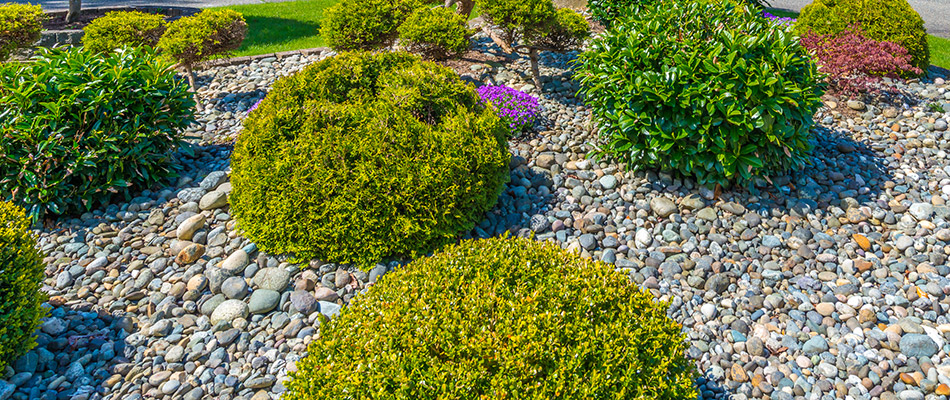 A landscape bed of bushes covered with rock by a home in Pleasant Hill, IA.