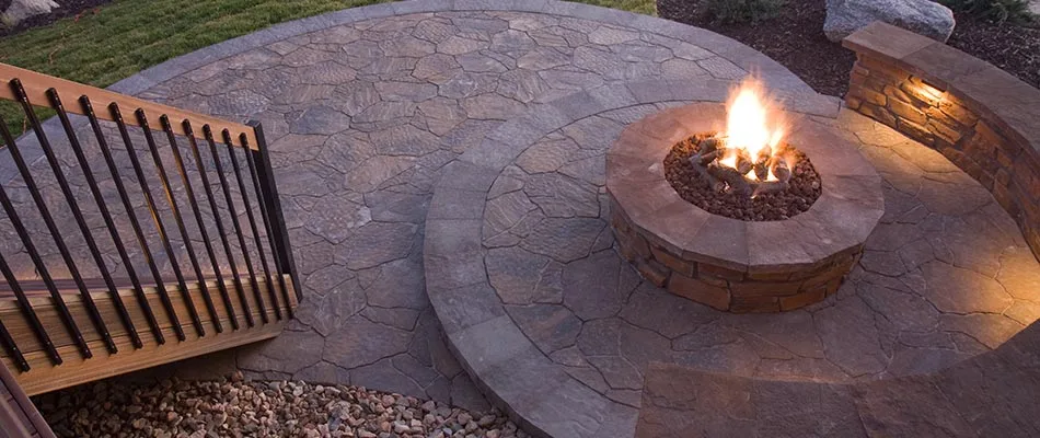 Fire pit with flames on a custom patio near Bondurant, IA.