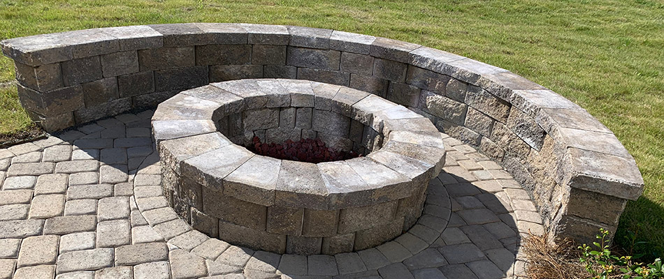 A fire pit with matching seating wall installed in the backyard of a home in Clive, IA.
