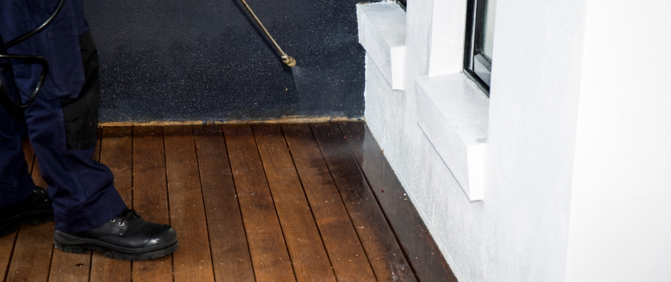 Professional applying perimeter pest control treatment to home in Ankeny, IA.