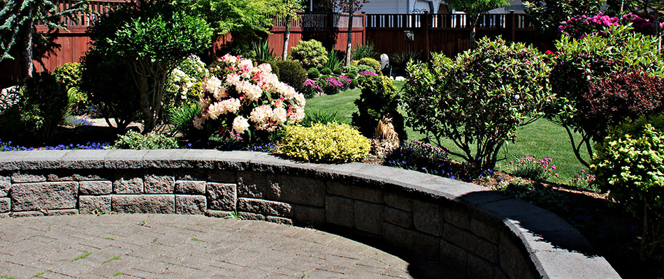 A seating wall surrounded by trees and flowers behind a home in Huxley, IA.