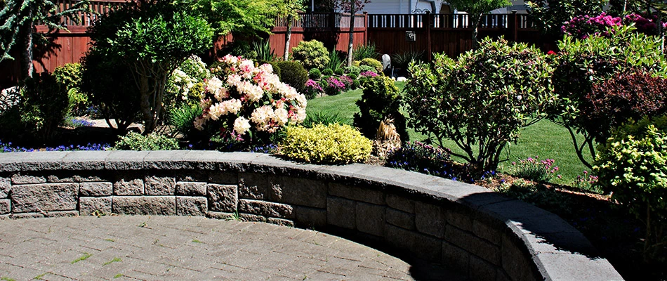 A seating wall surrounded by trees and flowers behind a home in Huxley, IA. 