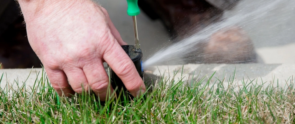 Tech repairing pressure of sprinkler head in lawn in Bondurant, IA.